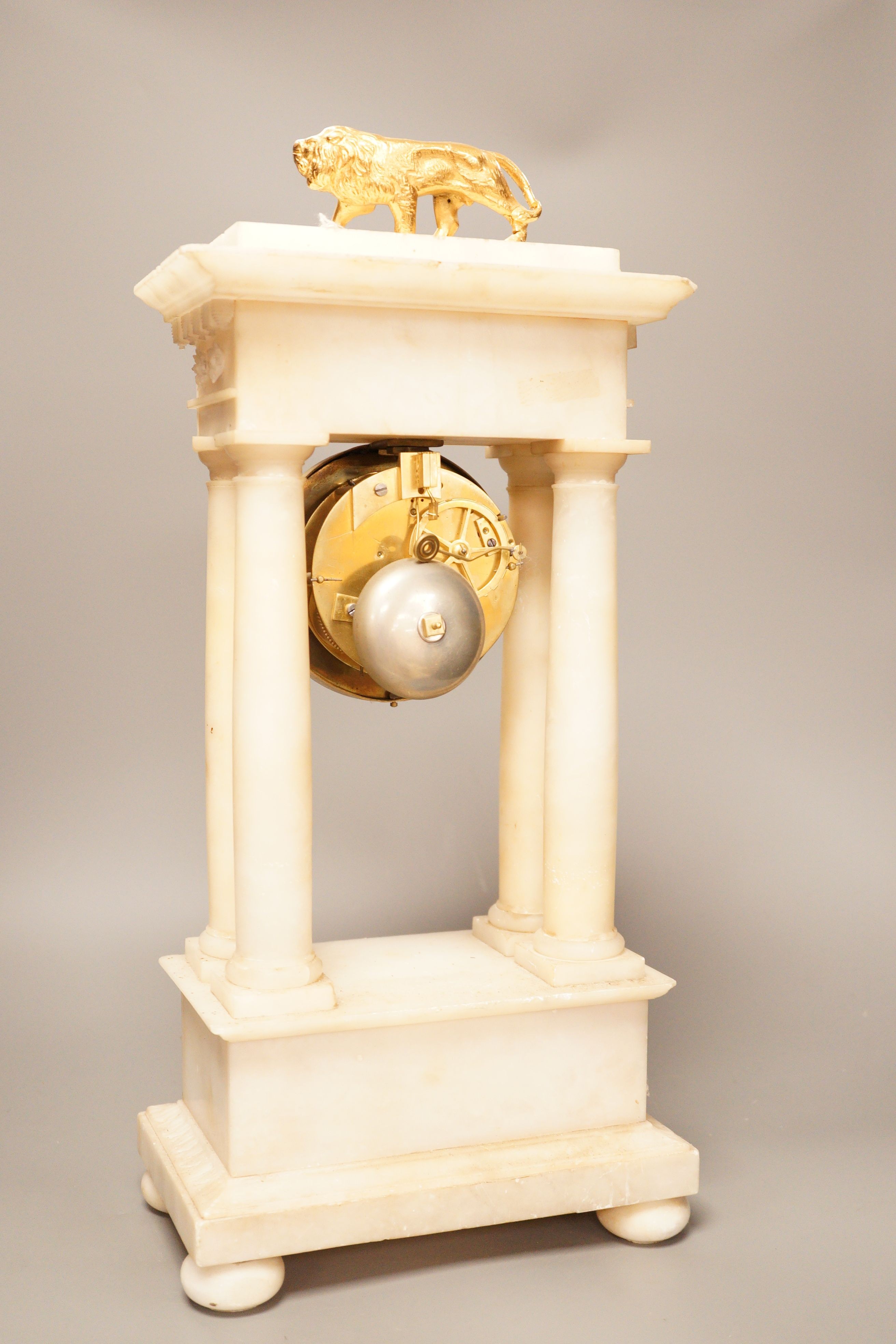 A 19th century alabaster portico clock with a gilt metal prowling lion decoration, 50cm tall